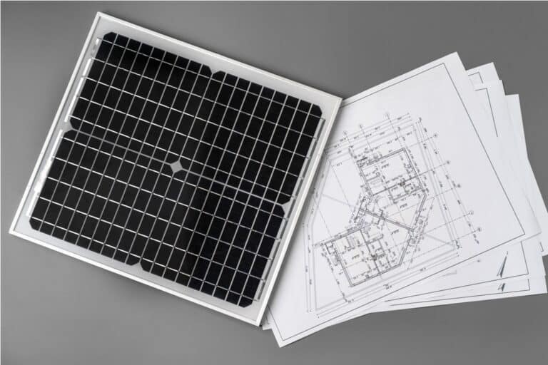 architectural blueprints and solar panel on table