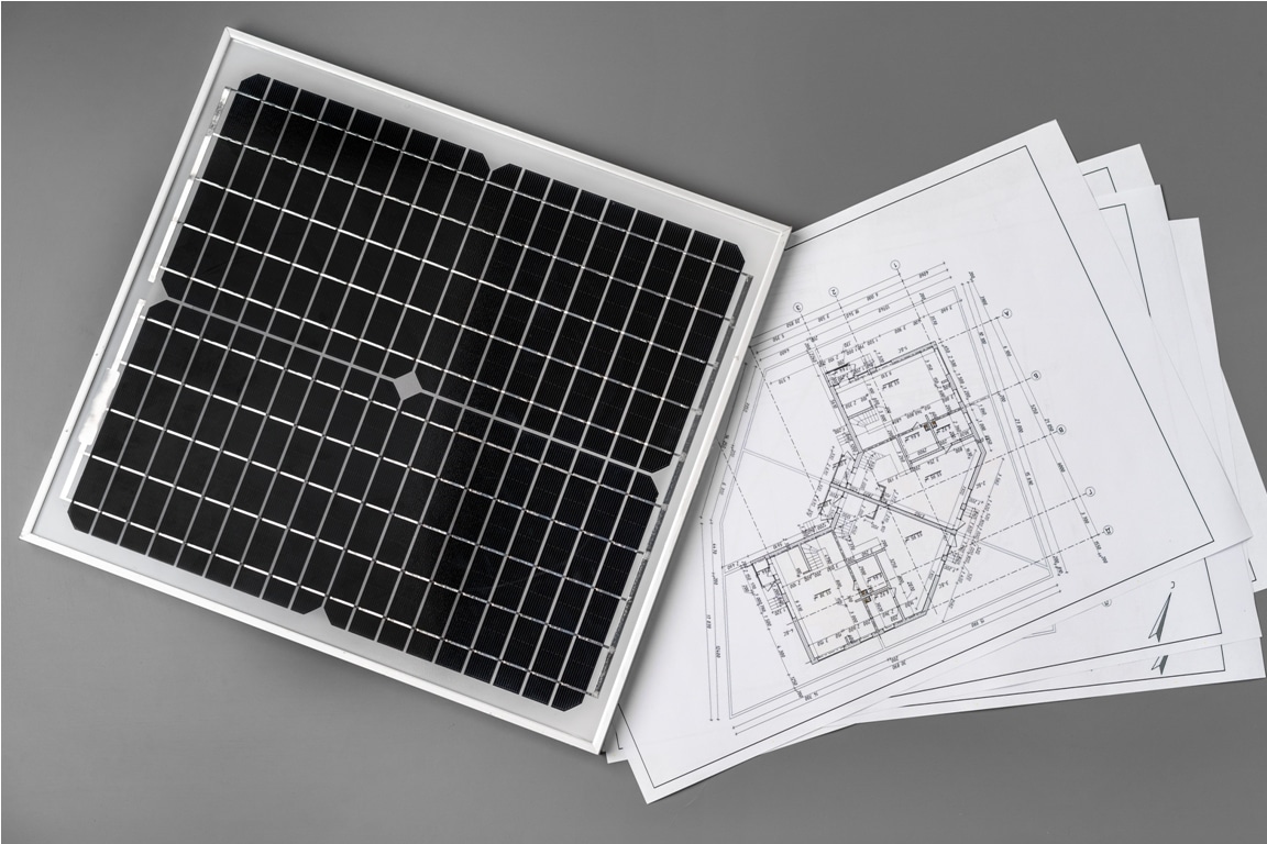 architectural blueprints and solar panel on table