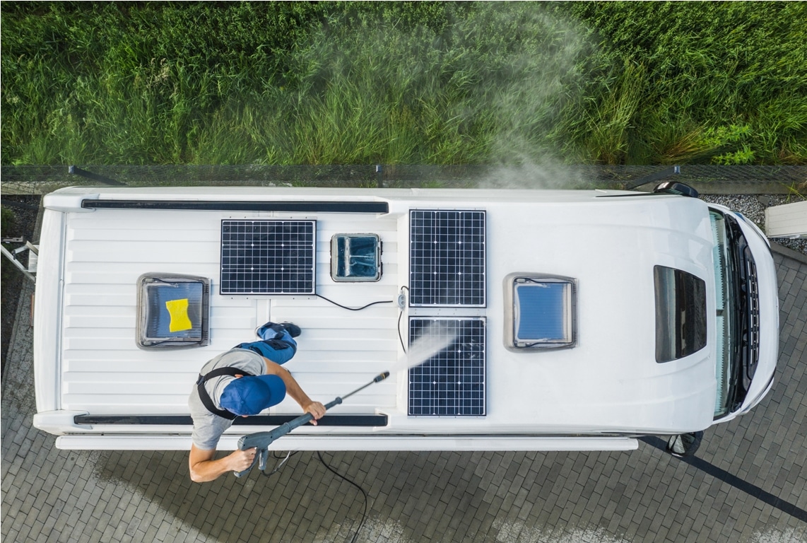 men pressure washing rv camper van roof equipped with solar panels