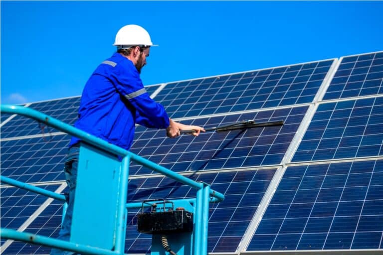 worker cleaning solar panel at solar cell farm