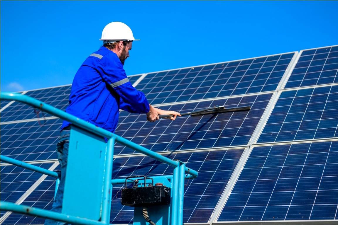 worker cleaning solar panel at solar cell farm