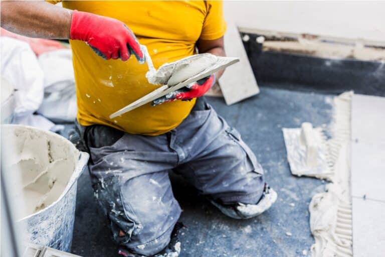 worker tiling house, cement on tile for the terrace floor